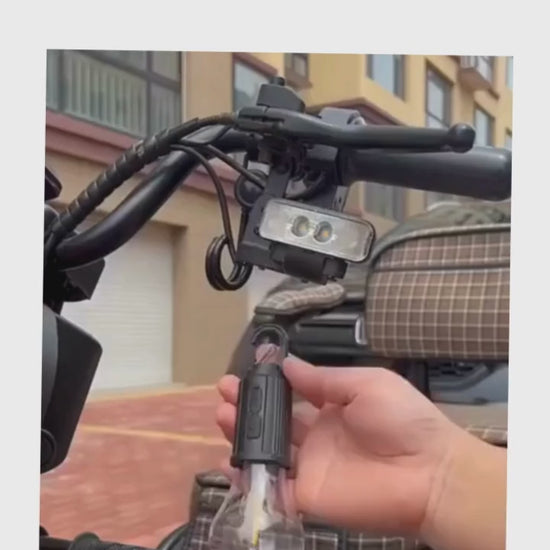 Person holding a rechargeable LED hanging bulb attached to a bike handle, showcasing versatile outdoor lighting.
